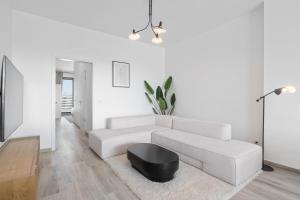 阿尔泽特河畔埃施Beautiful Penthouse close to University Esch的白色的客厅配有白色的沙发和黑色的搁脚凳