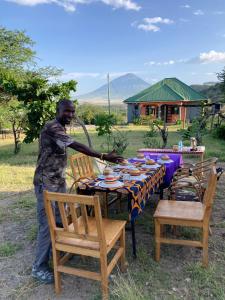MtowabagaLake Natron Maasai Guesthouse的站在桌子前,有一个人