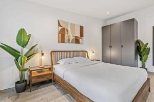 卢森堡Luxurious 2BR Apt with Balcony in Luxembourg的卧室配有白色的床和盆栽植物