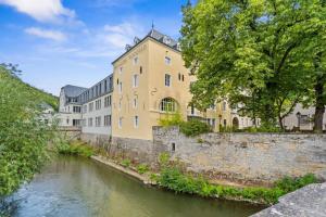 卢森堡Luxurious 2BR Apt with Balcony in Luxembourg的河边的黄色大建筑