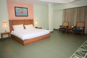乌贾因Hotel Ashray的一间卧室配有一张大床和两把椅子