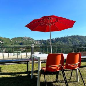 碧瑶Baguio BELL Staycation的一张桌子、两把椅子和一把红色雨伞