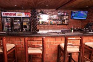 KitweSHERBOURNE LODGE的一个带砖墙的酒吧,配有椅子和柜台