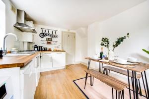 伦敦Heart of Hackney - 2bed garden flat sleeps 6的厨房配有白色橱柜和木桌