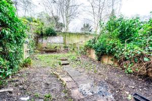 伦敦Heart of Hackney - 2bed garden flat sleeps 6的一座带石墙和树木的废弃花园