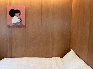 春川Chuncheon Diary Stay的卧室配有一张床,墙上挂有绘画作品