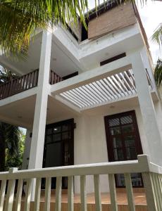 坦加拉Dinuri villa的白色的房子,设有门廊和阳台
