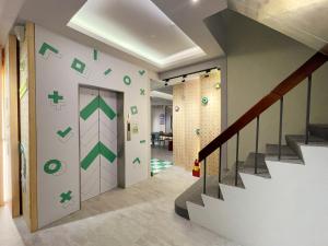 花莲市together hotel-Hualien Zhongshan的走廊上设有墙上绿色箭头的楼梯