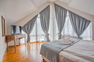 拉兹洛格Villa Deja Vu的一间卧室设有一张带电视和大窗户的床。