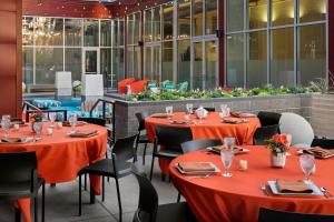 明尼阿波利斯Aloft Minneapolis的餐厅配有桌椅和橙色桌布