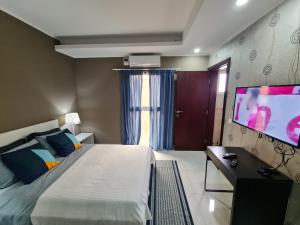 罗安达Lovely 5-Bed Suits - Guest House in Luanda的一间卧室配有一张床和一台平面电视