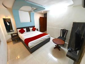 艾哈迈达巴德Hotel Sadbhav的一间卧室配有一张床、一台电视和一把椅子