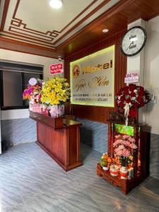 波来古市Motel Ngọc Hiền的大堂的墙上挂着时钟和鲜花