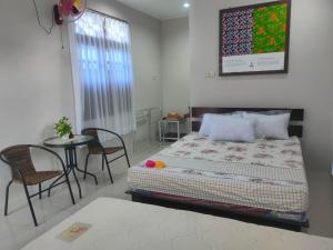 PasarbaruHomestay Erna Tanjong Tinggi的卧室配有一张床和一张桌子及椅子