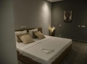 阿比让The Shelter Abidjan的卧室配有一张带白色床单和枕头的大床。