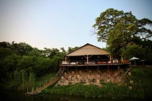 利文斯顿Zambezi Dusk的河边有帐篷的建筑
