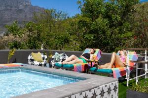 开普敦Cape Finest Guest House located in De Waterkant的三名妇女坐在游泳池旁的草坪椅上
