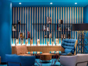 鲁瓦西昂法兰西宜必思巴黎戴高乐机场酒店的客厅设有蓝色椅子和书架