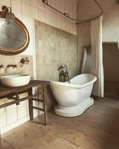 多尔德布列塔尼Domaine du tertre ychot的浴室设有2个水槽、浴缸和镜子
