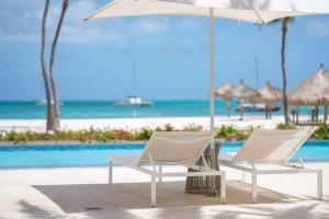 棕榈滩阿鲁巴岛凯悦度假酒店&赌场的游泳池旁的两把白色椅子和一把遮阳伞