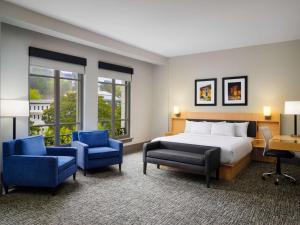 温泉城The Waters Hot Springs, Tapestry Collection by Hilton的酒店客房,配有一张床和两张蓝色椅子