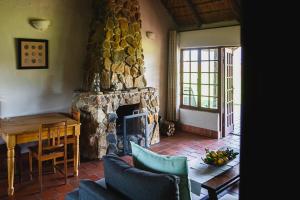 香槟谷Ardmore Guest Farm的客厅设有石制壁炉和桌子。