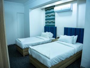 巴格达Malik Dijlah Hotel的配有白色床单的酒店客房内的两张床