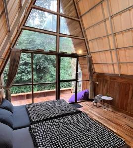 PalayanganLuxury cabin and cafe hutan pinus rahong的一间配有沙发和大窗户的客房