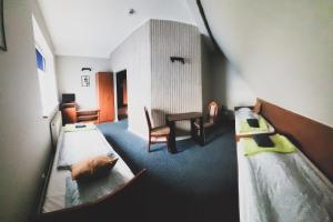 格涅夫Hotel Na Wzgórzu的一间设有两张床、一张桌子和一把椅子的房间