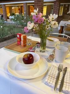 哈里史密斯Village Lodge Harrismith的一张带一盘食物和鲜花的白色桌子