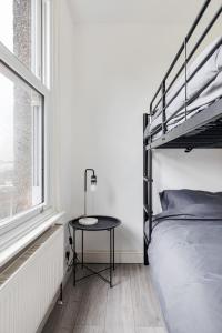 伦敦Stylish 2-Bedroom Flat in Walthamstow的一间卧室配有一张双层床和一张靠窗的桌子
