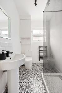 伦敦Stylish 2-Bedroom Flat in Walthamstow的白色的浴室设有水槽和卫生间。