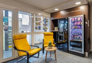 坎佩尔B&B HOTEL Quimper Nord Douarnenez的一间设有两把椅子和饮料冰箱的等候室