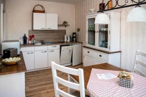 吕本瑙FEWO Hafenblick的厨房配有白色橱柜和一张带粉红色桌布的桌子。