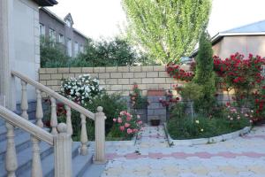 久姆里Sargsyan’s House的一座花园,花园内种有红白色的花卉,并拥有砖墙