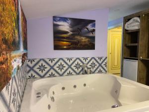 阿拉尼亚Castle Light Boutique的浴室设有白色浴缸,墙上挂有绘画作品