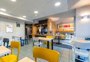 维拉尔B&B HOTEL Saint-Etienne La Terrasse的餐厅内带桌椅的用餐室