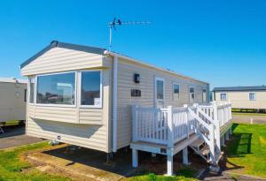 坎伯利SP158 - Camber Sands Holiday Park - 3 Bedrooms - Second Toilet - Decking - Private Parking的停车场里的一个白色小房子