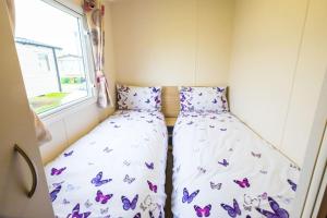 坎伯利SP158 - Camber Sands Holiday Park - 3 Bedrooms - Second Toilet - Decking - Private Parking的小房间设有两张床,蝴蝶就放在上面