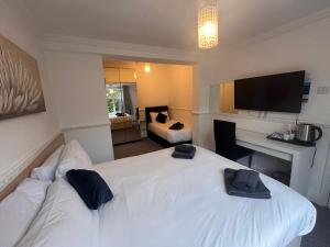 拉夫堡Charnwood Regency Guest House的酒店客房设有白色的床和电视。
