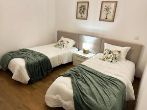 莫什港Largo das Calçadas的客房设有两张床和一张带台灯的桌子。