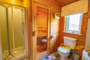 BrooklandTore Petty - Romantic lodge - spa bath and sauna的带淋浴和卫生间的木制浴室