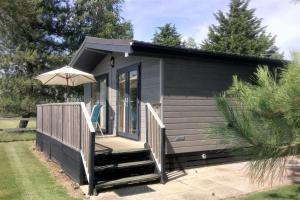 BrooklandTore Petty - Romantic lodge - spa bath and sauna的一座带甲板和遮阳伞的小房子