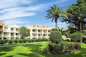 戛纳Résidence Cannes Villa Francia - maeva Home - Appartement 2 pièces 5 perso 634的一座棕榈树大建筑,草坪