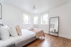 伦敦Stylish 3-bed near Camden Town & King's Cross的白色卧室配有床和镜子