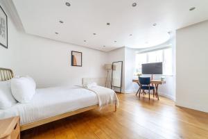 伦敦Stylish 3-bed near Camden Town & King's Cross的白色卧室配有一张大床和一张书桌