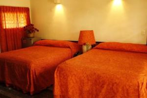 科苏梅尔白墅海滨花园酒店的酒店客房带两张带橙色床单的床