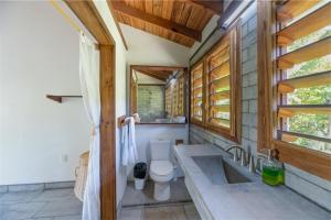 罗阿坦Camp Bay Lodge的一间带卫生间、水槽和窗户的浴室
