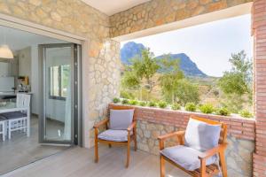 埃尔加斯托尔3 bedrooms chalet with private pool terrace and wifi at El Gastor的一个带两把椅子的庭院和大窗户