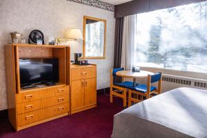班夫包湖景观酒店的一间酒店客房,配有一张床、一台电视和一张桌子